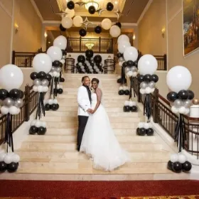 Balloon decorations in the stairs and groom and bride standing in the center of stage